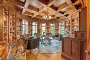 A library with wooden bookshelves, leather chairs, and a chandelier. - River views, guest house and pool (Kiawah Island)