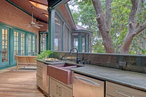 A kitchen with a built-in sink, wooden cabinets, and a large window overlooking a tree. - River views, guest house and pool (Kiawah Island)