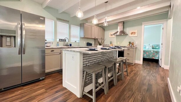 Una cucina moderna con isola centrale, elettrodomestici in acciaio inossidabile e pavimento in legno.