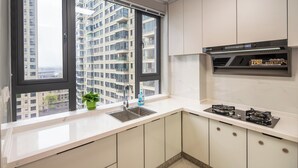 A modern kitchen with a large window, a sink, a stove, and cabinets. - Serveyou Apartment (Chengdu)