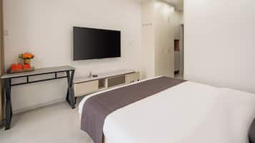 Een moderne hotelkamer met een groot bed, een flatscreen televisie aan de muur, een bureau met een stoel en een kledingkast.