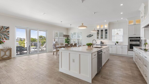 Una cocina amplia con una isla grande, armarios blancos y vistas al exterior.
