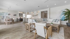 Amplia sala de estar con sofá blanco, mesa de centro de madera y juego de mesa de comedor.