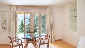 A room with a glass table and chairs, a large window with curtains, and a white wardrobe.