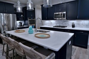 A modern kitchen with dark cabinets, stainless steel appliances, and a white countertop.