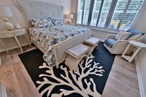 A bedroom with a bed, bedside tables, a chair, and a window with blinds.
