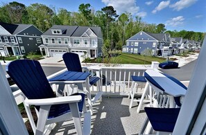 A balcony with Adirondack chairs, a view of residential buildings, and a clear sky.
