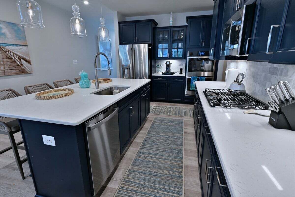 A modern kitchen with dark cabinets, stainless steel appliances, and a central island.