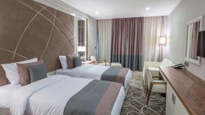 Une chambre d’hôtel avec deux lits, un bureau, une chaise et un téléviseur.