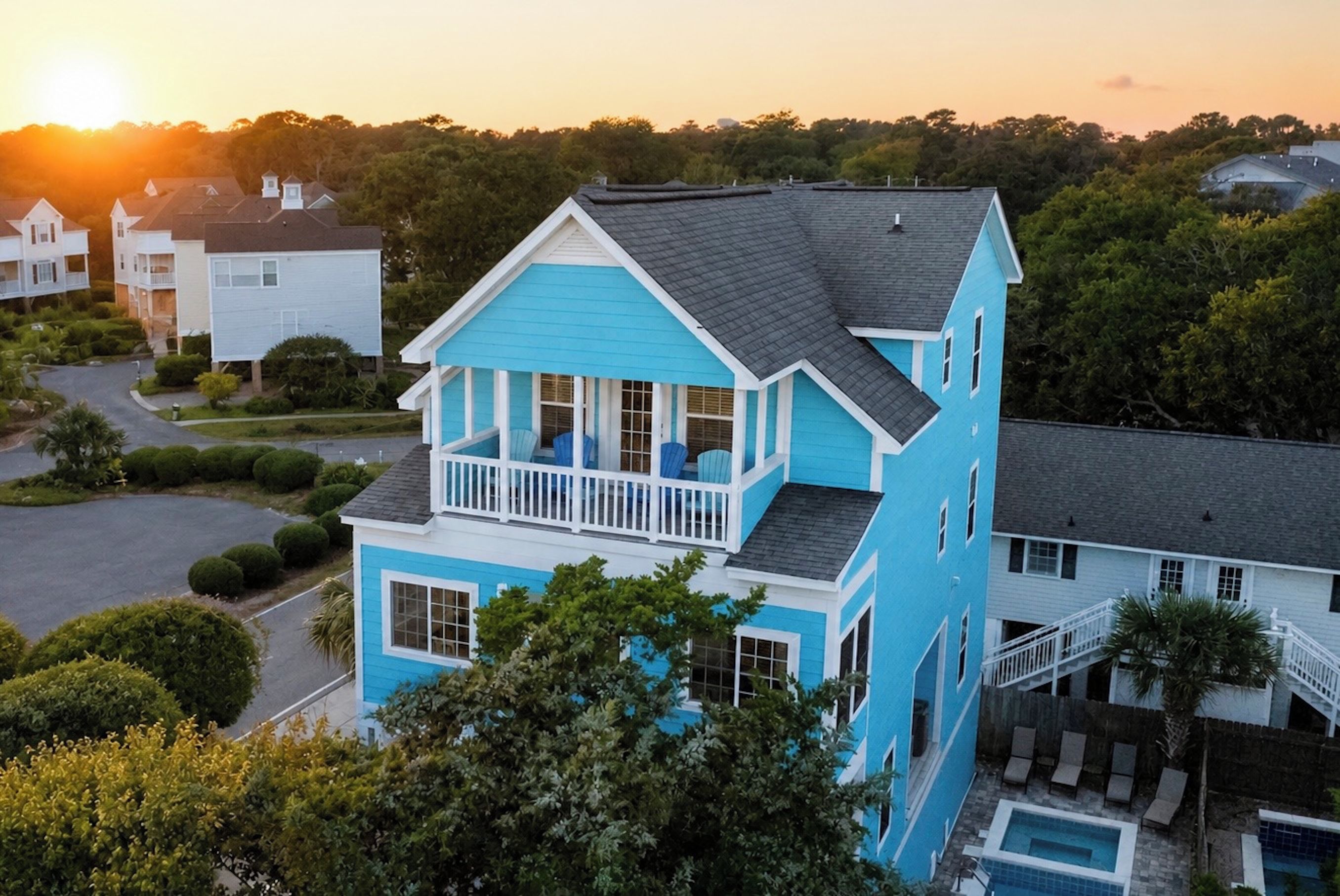 A two-story house with a balcony, a swimming pool, and a driveway.
