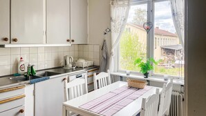 A kitchen with white cabinets, a kettle, a sink, and a window with curtains. - 1 bedroom amazing apartment in Orrefors (Orrefors)