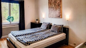A bedroom with two beds, a window with curtains, a radiator, a wall-mounted map, and two wall-mounted lights. - 1 bedroom amazing apartment in Orrefors (Orrefors)