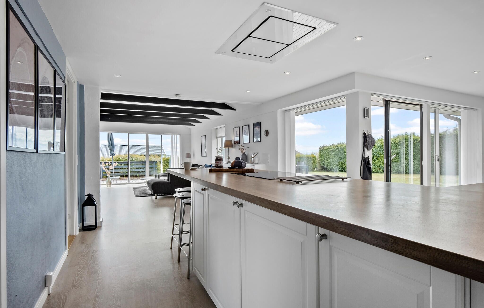 A modern kitchen with a central island, white cabinetry, and a large sliding glass door leading to a patio.