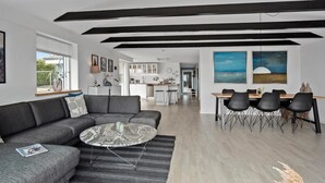 A modern living room with a grey sofa, a marble coffee table, and a dining area with a wooden table and black chairs. - Stunning home in Faaborg (Faaborg)