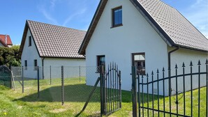 A white building with a sloped roof, a chain-link fence, and a metal gate.