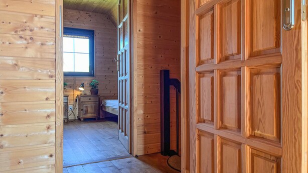 A wooden interior with a wooden door, a window, and a small kitchenette area.