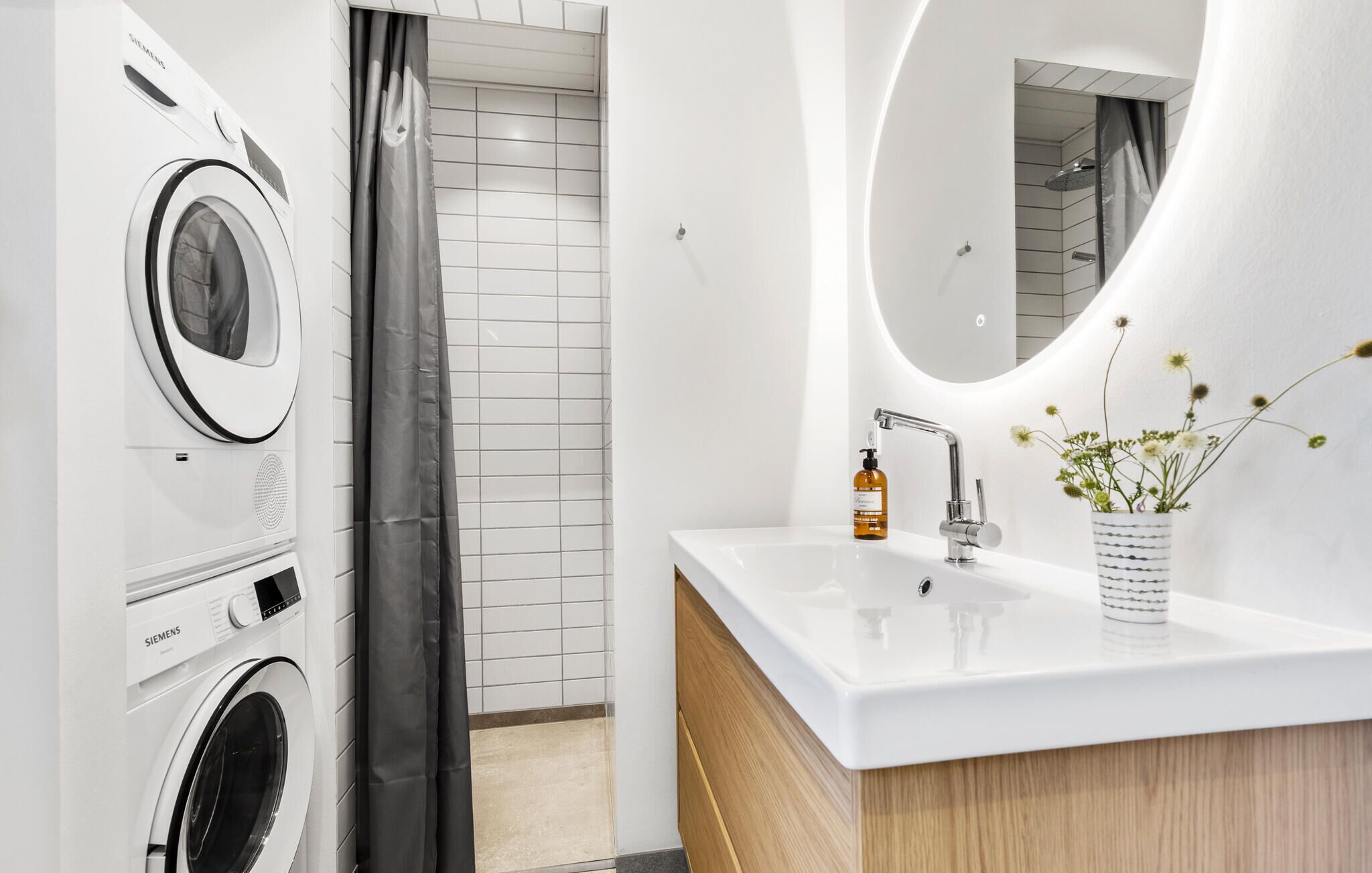 A modern bathroom with a white sink, a mirror, and a shower.
