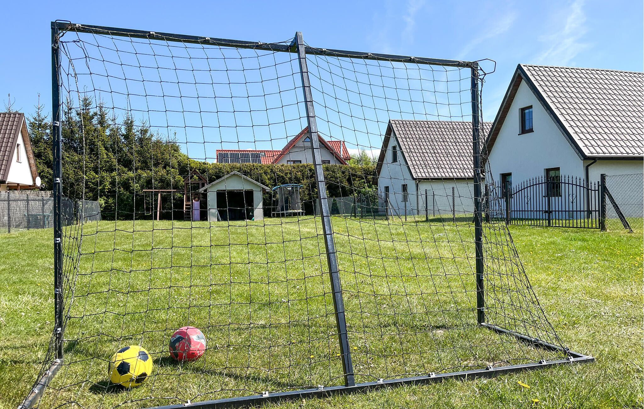 Ein Fußballtor in einer grünen Wiese, im Hintergrund Häuser.