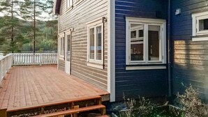 A two-story house with a wooden deck and a blue exterior wall.