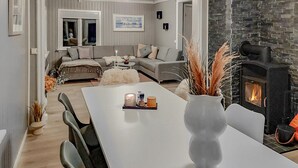 A modern living room with a white table, a fireplace, and a grey sofa.