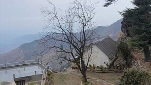 A residential area with a house, a fenced garden, and a view of mountains. - HOTEL PHOENIX (Mussoorie)