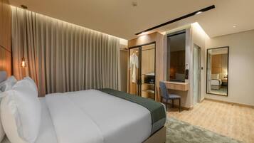 Una habitación de hotel con una cama, un escritorio, una silla, un espejo y un armario.