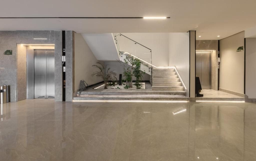 A modern lobby with a polished floor, a staircase, and a reception area.