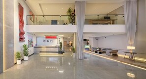 Un vestíbulo amplio con mostrador de recepción, área de estar y escalera que conduce a un nivel superior.
