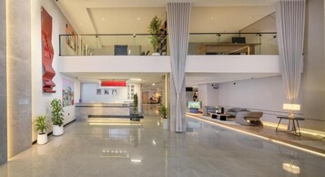 A spacious lobby with a reception desk, seating area, and a staircase leading to an upper level.