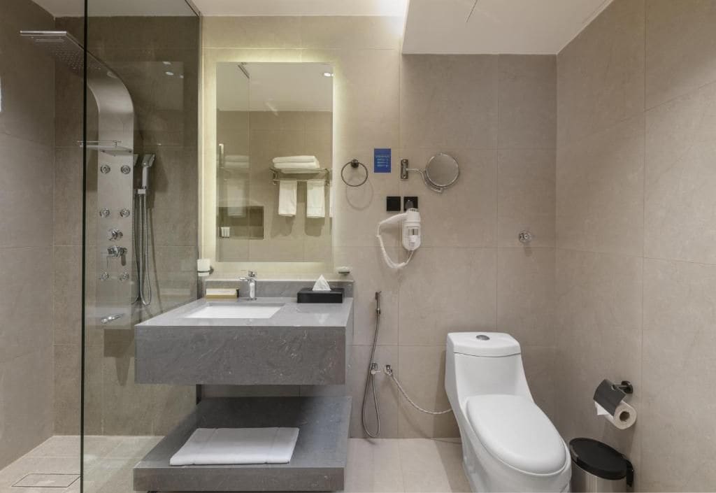 A modern bathroom with a glass-enclosed shower, a sink with a towel, and a toilet.