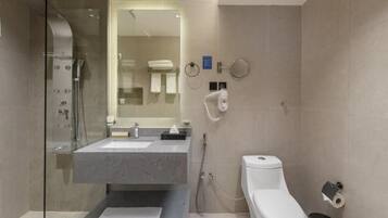 A modern bathroom with a glass-enclosed shower, a sink with a towel, and a toilet.