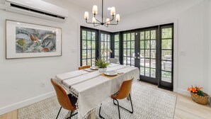 A dining area with a table set for two, a chandelier, a potted plant, and a framed artwork on the wall. - Private Beach + Outdoor Oasis: Home in St Pete! (St. Petersburg)