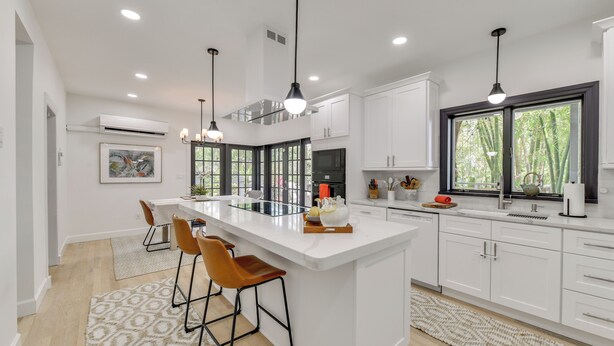 A modern kitchen with a large island, pendant lighting, and a view of greenery outside. - Private Beach + Outdoor Oasis: Home in St Pete! (St. Petersburg)
