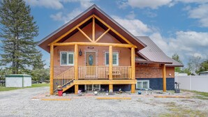 A two-story lodge with a wooden balcony, a covered front porch, and a brick facade.