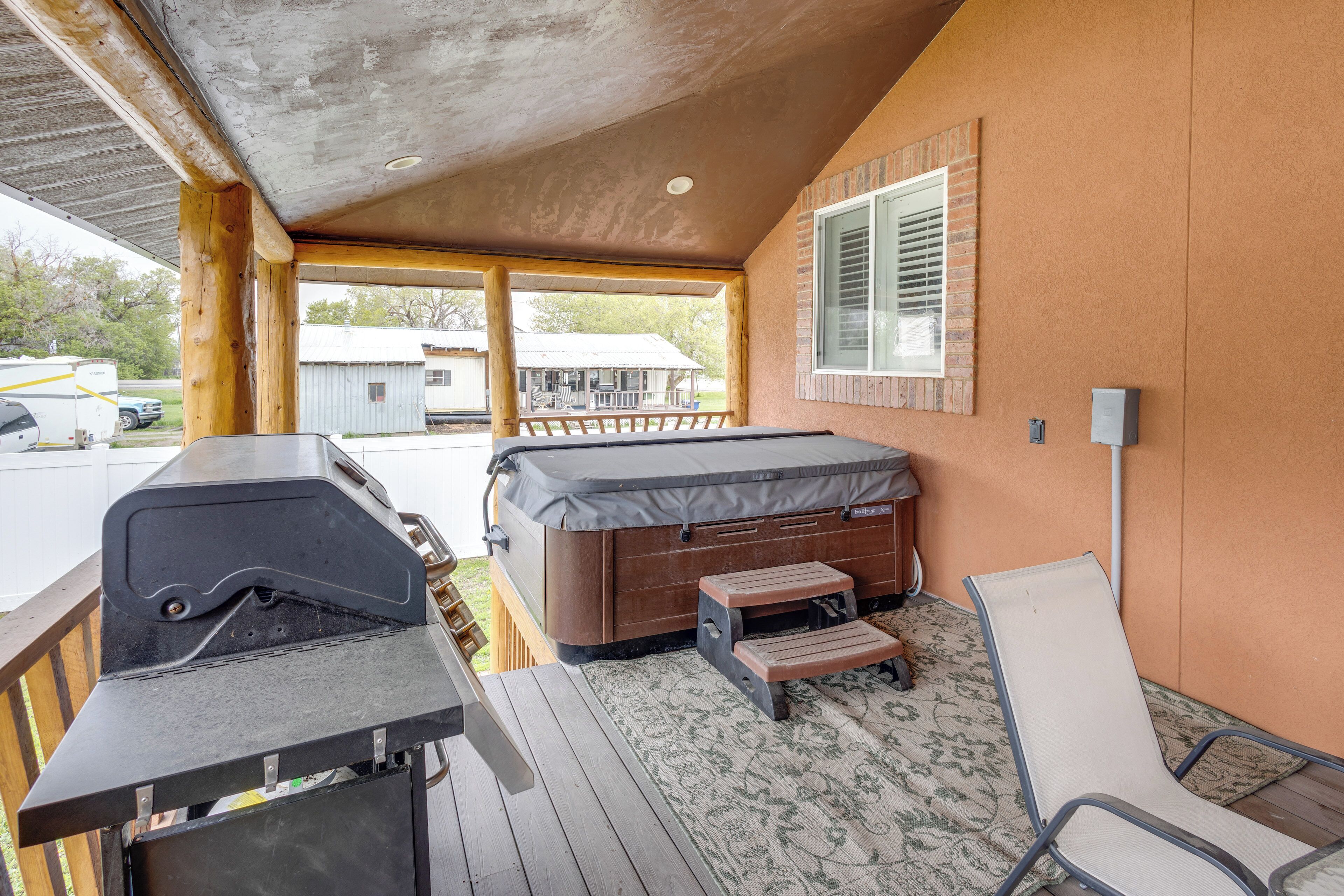 Un espace extérieur abrité comprenant un barbecue, un jacuzzi et un fauteuil de relaxation.