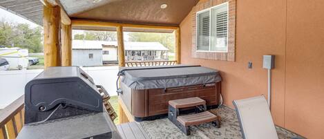 Un espace extérieur abrité comprenant un barbecue, un jacuzzi et un fauteuil de relaxation.