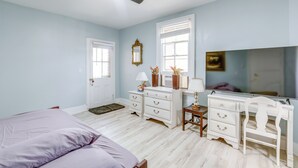 Un dormitorio con cama, cómoda, tocador y ventilador de techo.