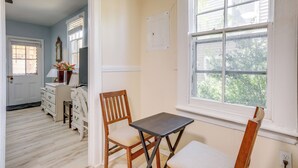 Una habitación con una silla de madera, una mesita, un aparador y una ventana con persianas.