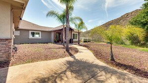 A residential house with a concrete driveway, palm trees, and a hilly landscape in the background. - Family Hideaway w/ Hillside Views in Temecula! (Temecula)