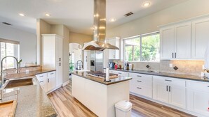 A modern kitchen with white cabinetry, a central island, and a stainless steel range hood. - Family Hideaway w/ Hillside Views in Temecula! (Temecula)