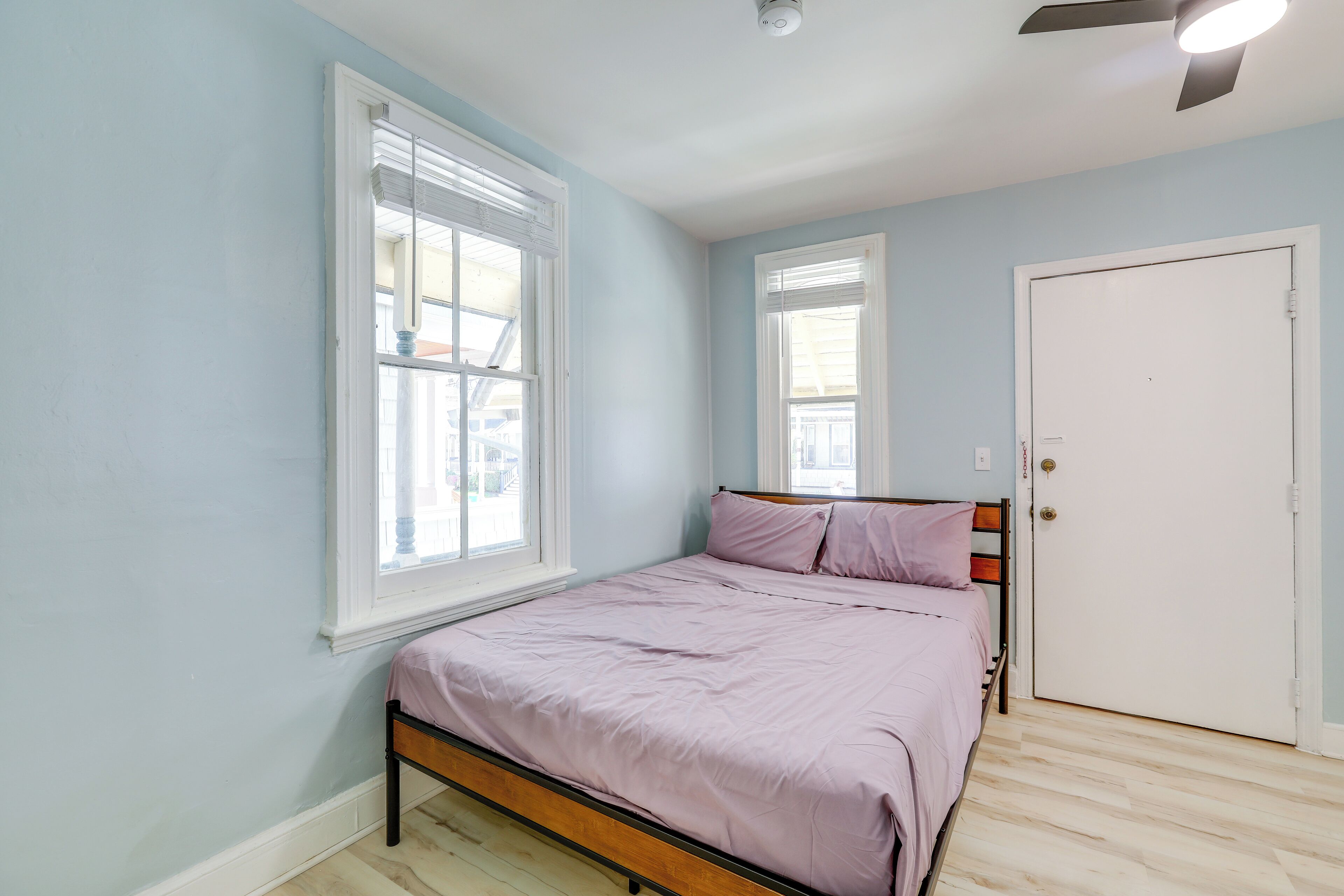A bedroom with a single bed, light blue walls, and a white door.