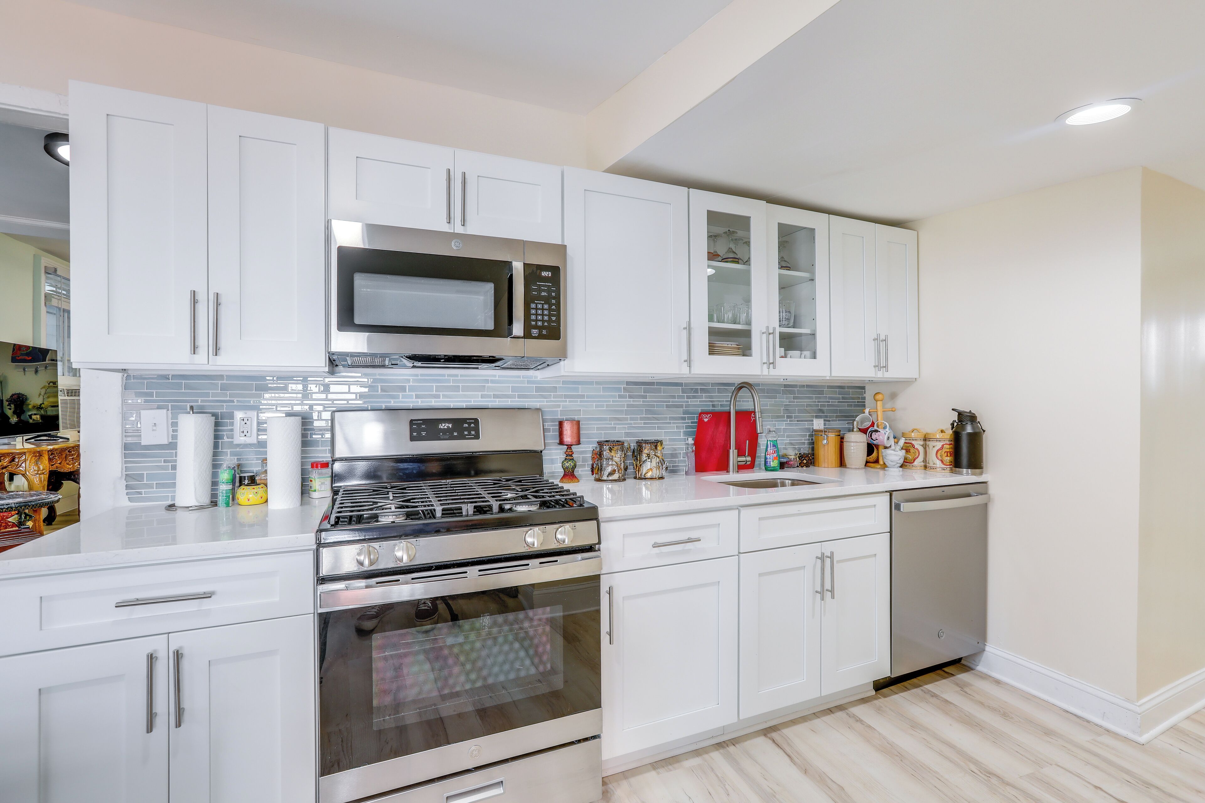 A modern kitchen with white cabinets, stainless steel appliances, and a tiled backsplash.