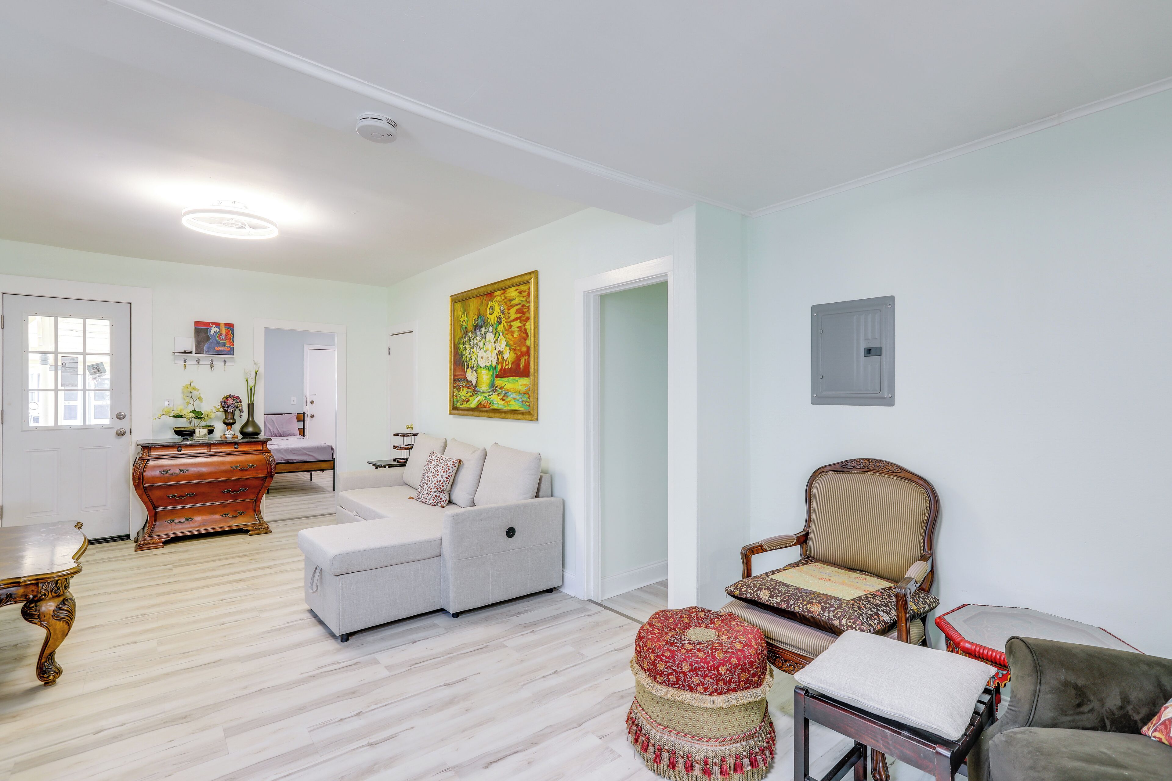 Un salon spacieux comprenant un canapé, un fauteuil, un pouf et un meuble en bois.