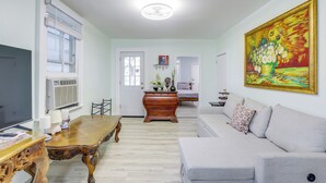 A living room with a sofa, a wooden coffee table, and a painting on the wall. - Walk to Ocean Grove Beach: Apt in New Jersey (Ocean Grove)