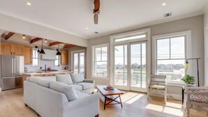 A spacious living room with a grey sofa, wooden flooring, and large windows offering a city view. - Steps From Sand & Fun: Beach Haven Retreat w/ Pool (Beach Haven)