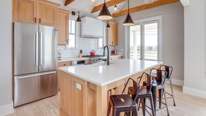 A modern kitchen with wooden cabinets, stainless steel appliances, and a large island with bar stools. - Steps From Sand & Fun: Beach Haven Retreat w/ Pool (Beach Haven)