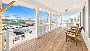 A wooden deck with white railings and a view of a marina and buildings. - Steps From Sand & Fun: Beach Haven Retreat w/ Pool (Beach Haven)