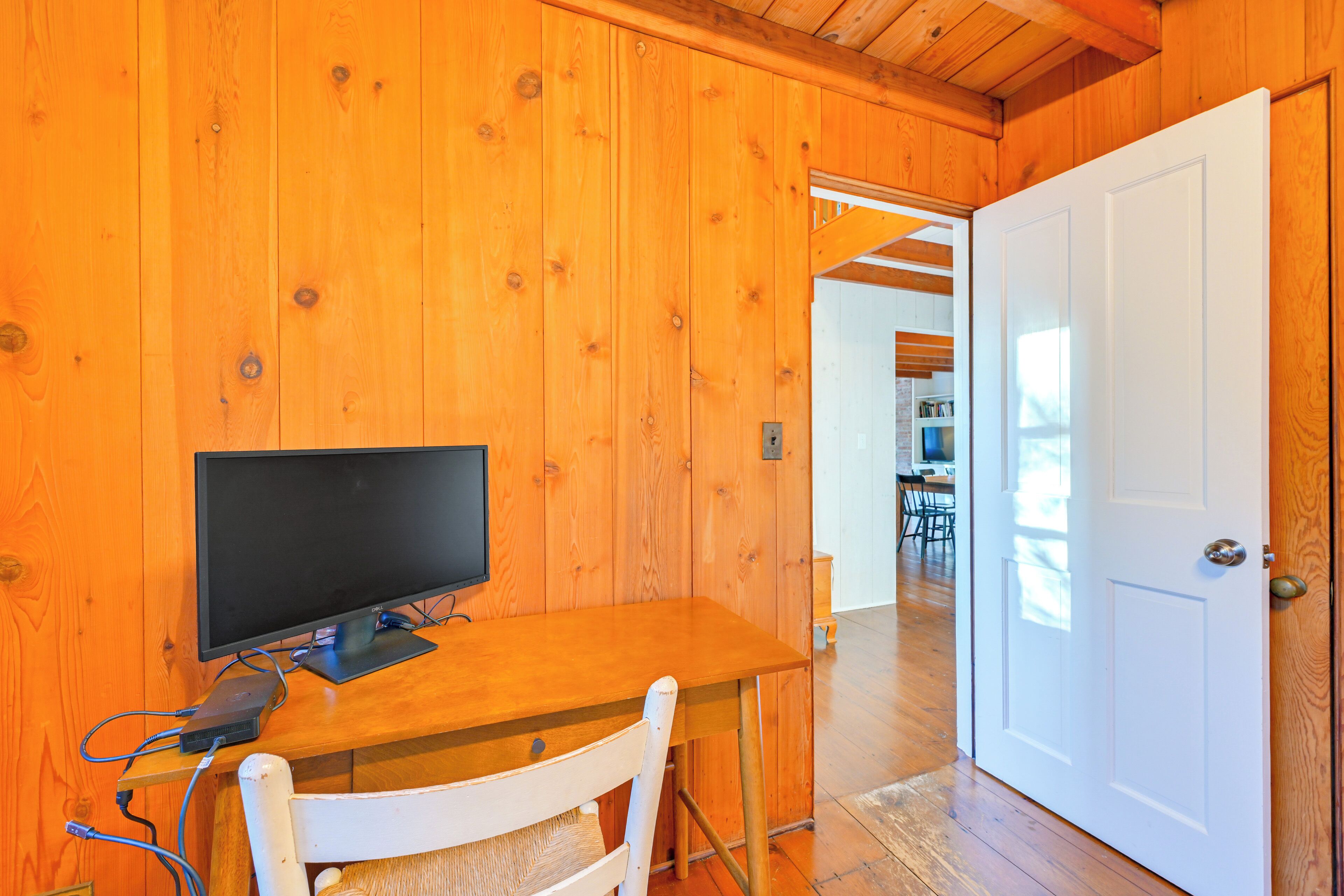 Ein Holzinterieur mit einem Tisch, auf dem ein Fernseher steht, einem weißen Stuhl und einer Tür zu einem anderen Raum.