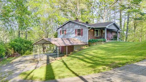A two-story house with a covered porch, surrounded by a well-maintained lawn and trees. - 1 Mi to Pisgah Natl Forest: Wooded Haven w/ Deck (Pisgah Forest)