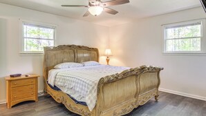 A bedroom with a large ornate bed, a nightstand, a ceiling fan, and two windows with natural light. - 1 Mi to Pisgah Natl Forest: Wooded Haven w/ Deck (Pisgah Forest)